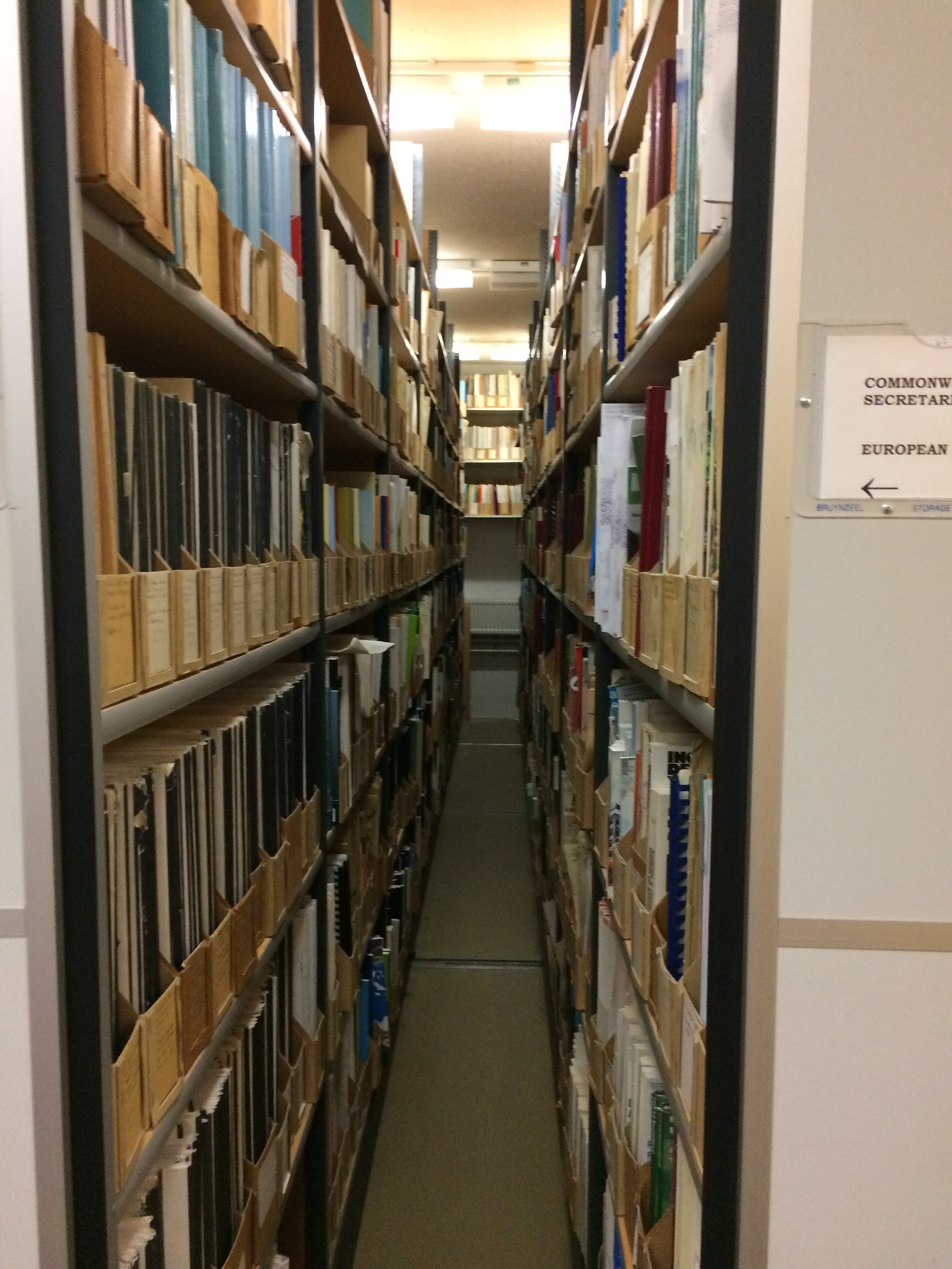 Two rows of wooden shelving encased in metal, very small gap between shelves, shelves packed full with old BLDS pamphlet boxes