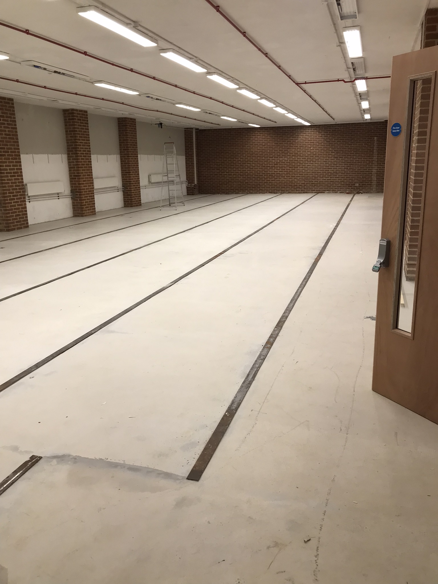 Large empty room with white floor, and red brick walls