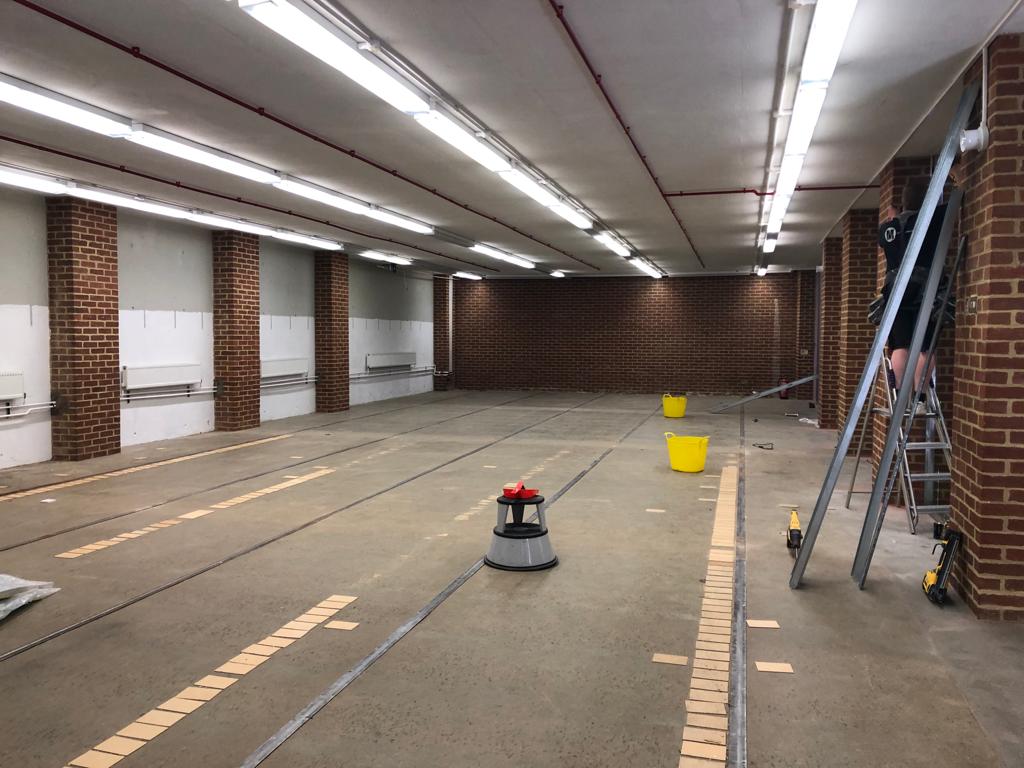 Large empty room with old grey floor, and red brick walls
